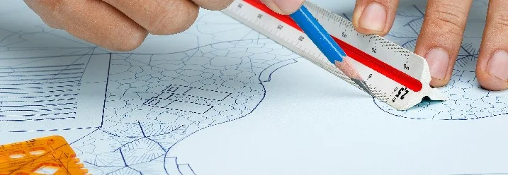 Hände zeichnen mit Lineal und Stift auf Plan